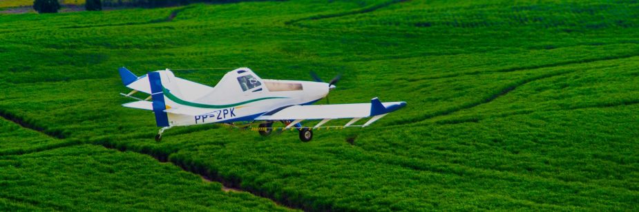 Foto de aeronave sobrevoando plantação para realizar pulverização de defensivos agrícolas